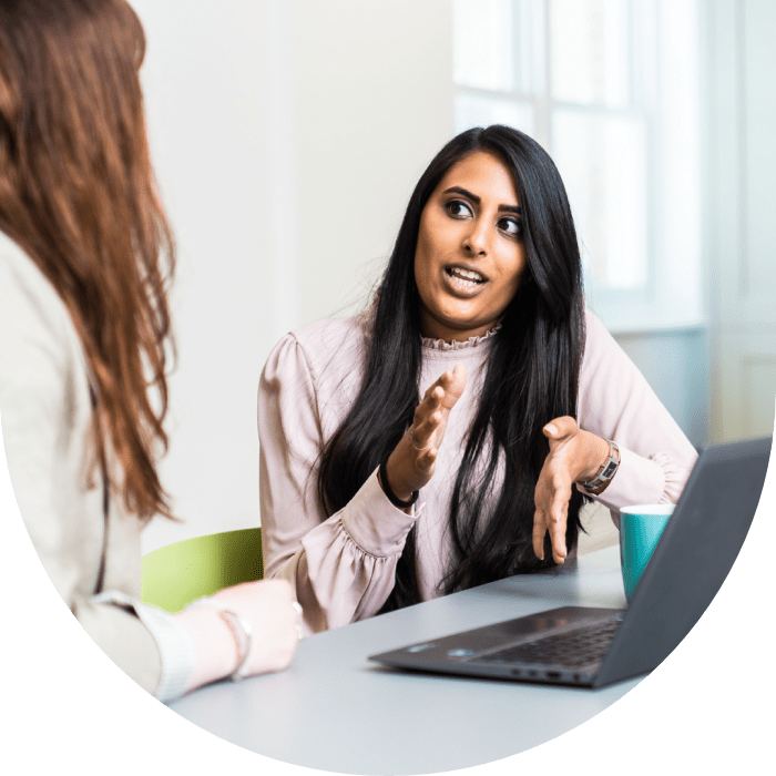 A smiling woman in conversation with a colleague