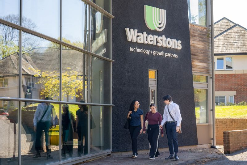 Colleagues walking in front of a waterstons building
